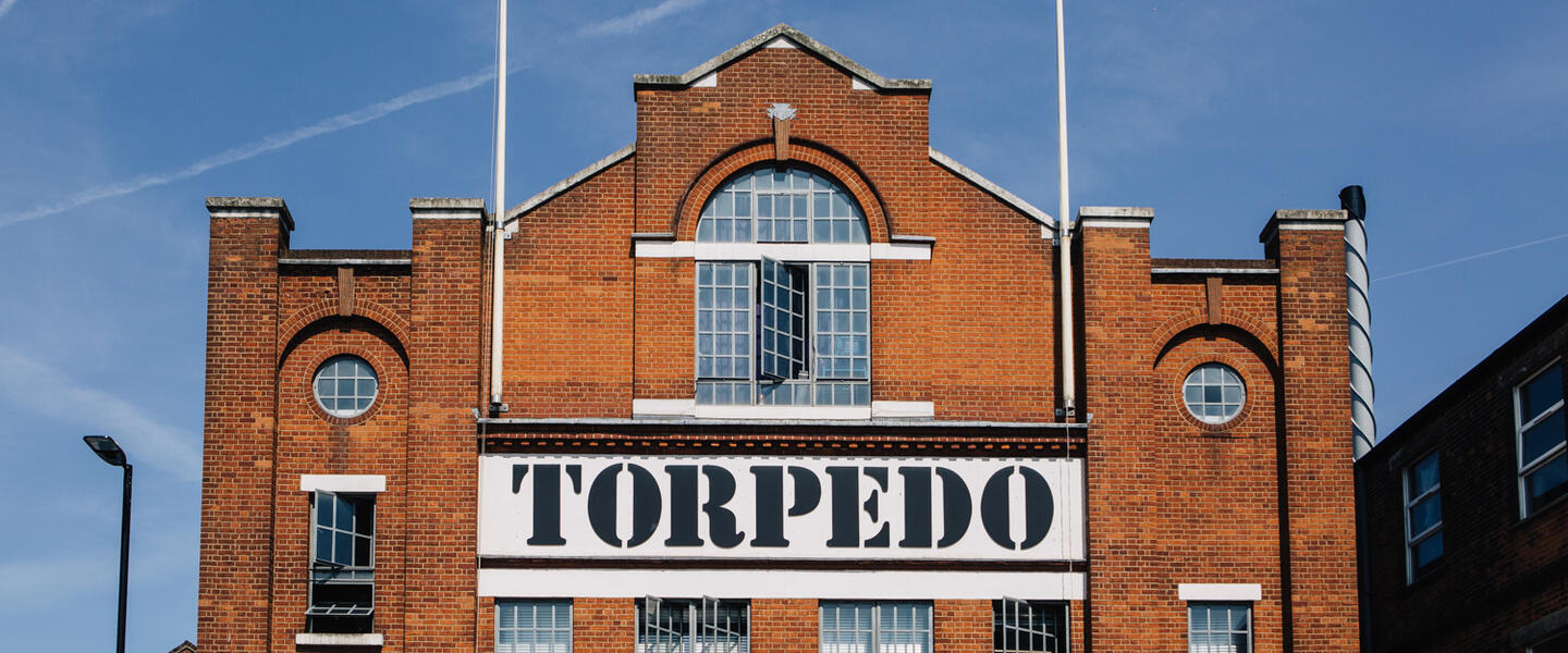 Image of a red brick factory with the words Torpedo on