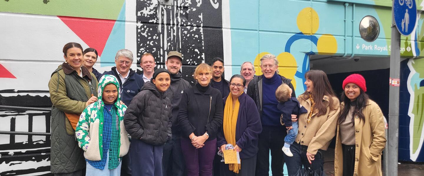 Image of a group of people stood in front of a vibrant mural