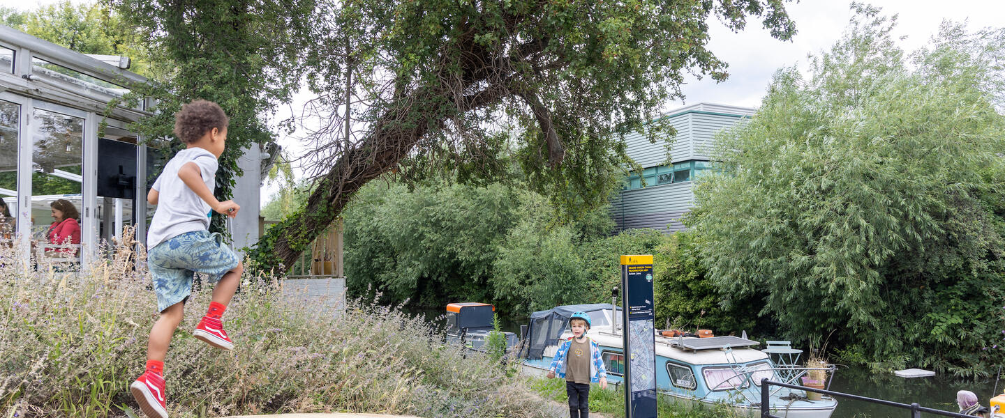 Child jumping along a path which runs alongside a canal