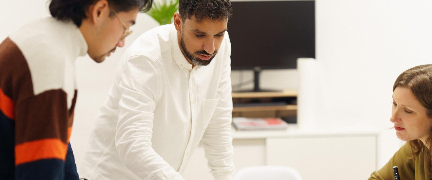 Image of three people looking at architectural plans on a table