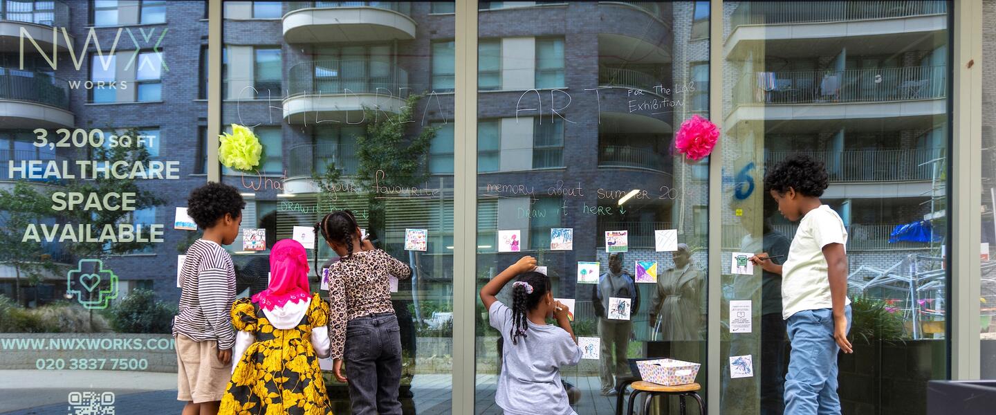 Image of a group of children sticking post it notes with their art on to a glass wall