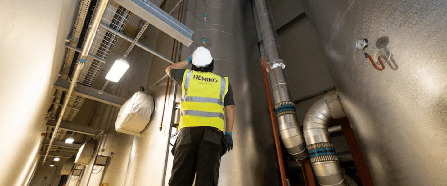 Image of a man in a hi-vis jacket stood in front of large pipes under ground
