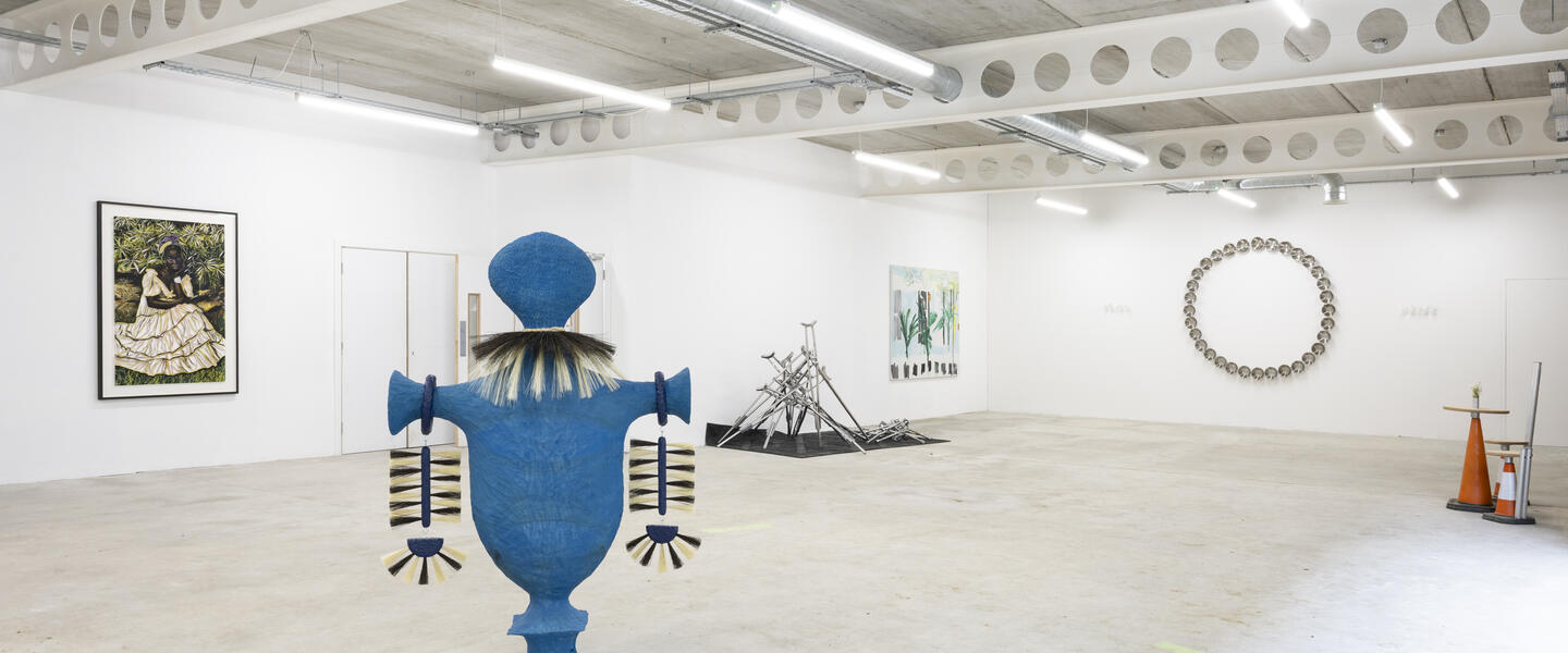 A gallery space with large blue sculpture and painting in the background