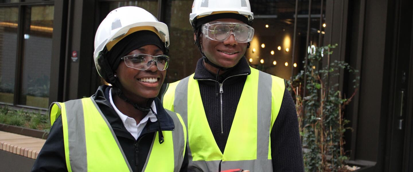 Two young people in high vis jackets and hard hats