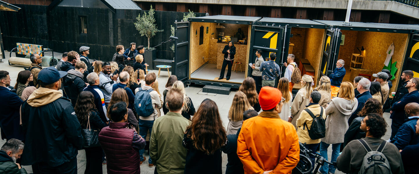 Large group stood in front of shipping containers in North Acton Square