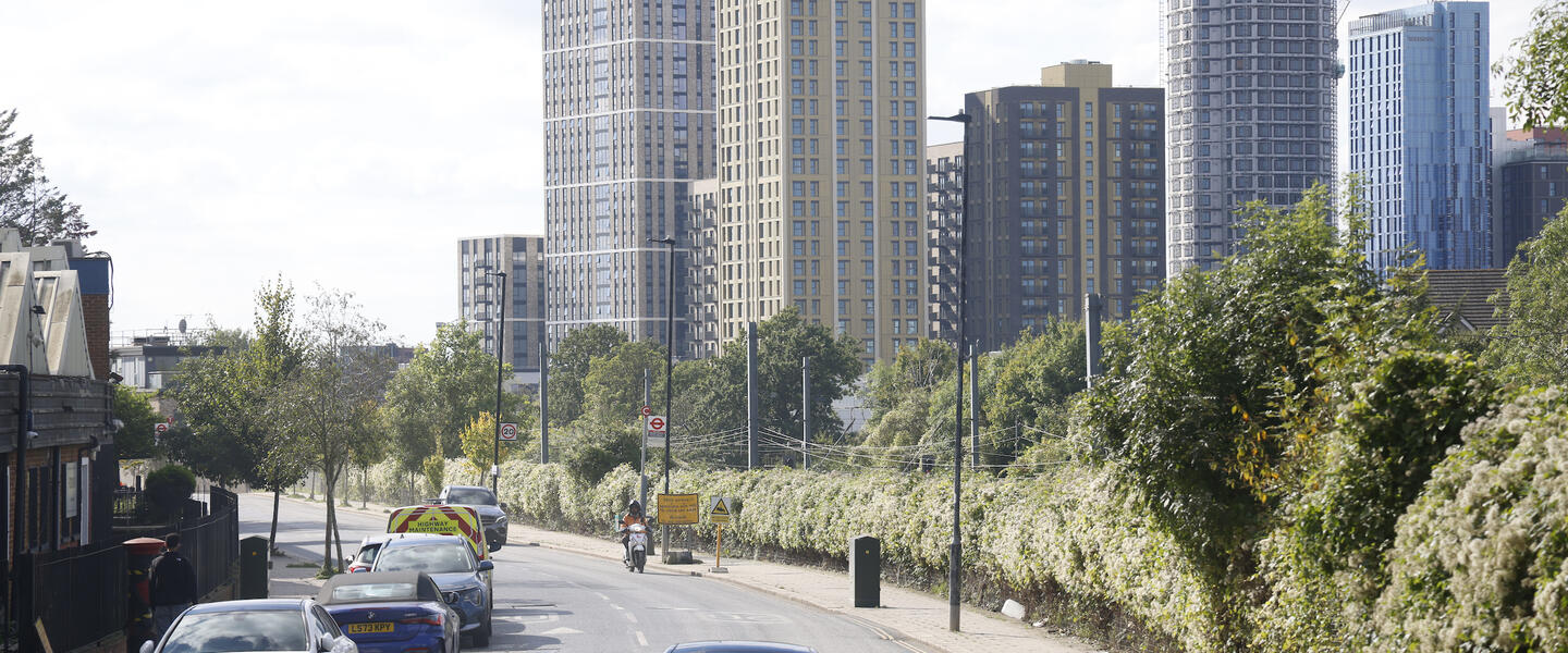 A road alongside a green space, with sky scrapers in the background