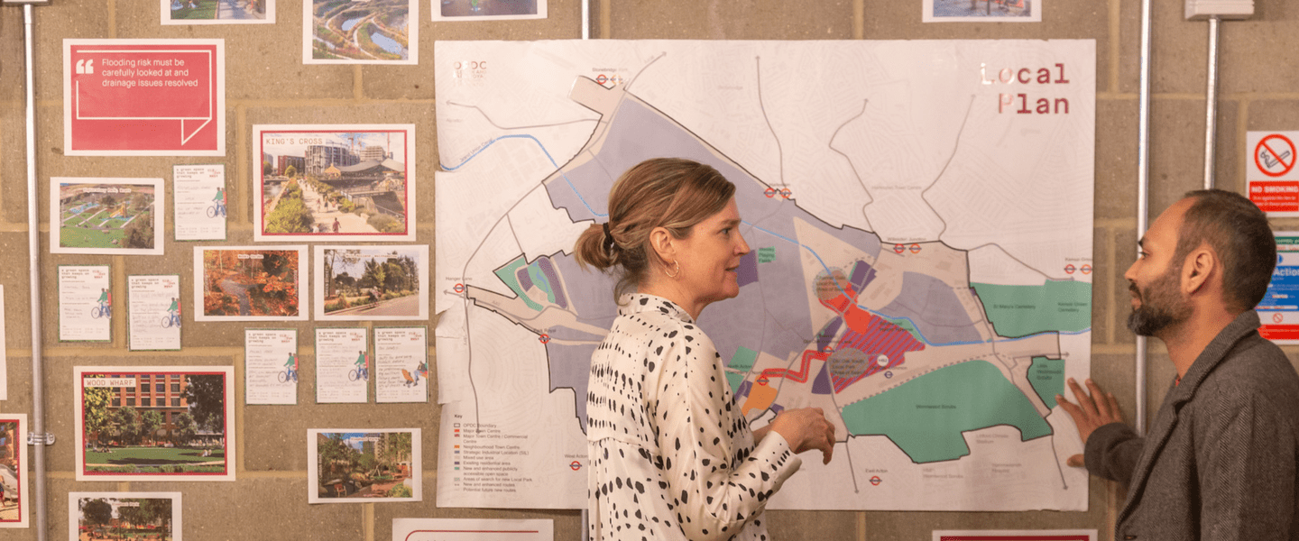 Image of two people stood in front of boards featuring a map and other photos