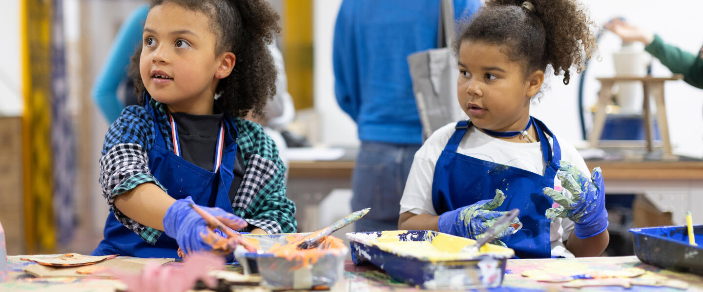 Two young children in a workshop with aprons on