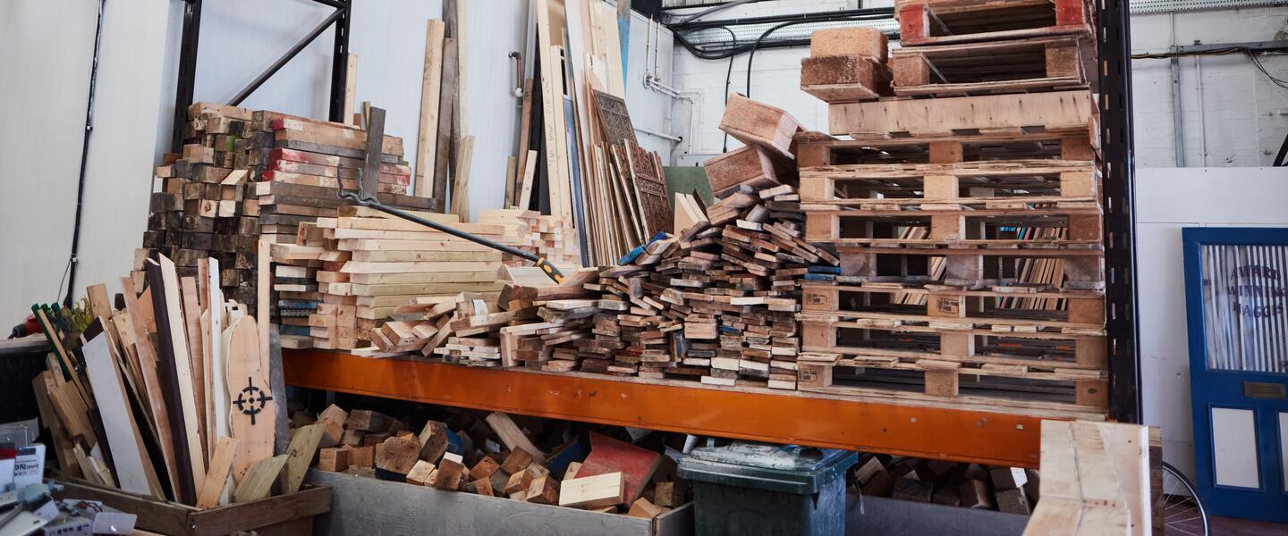 An industrial setting with piles of waste wooden planks and palettes
