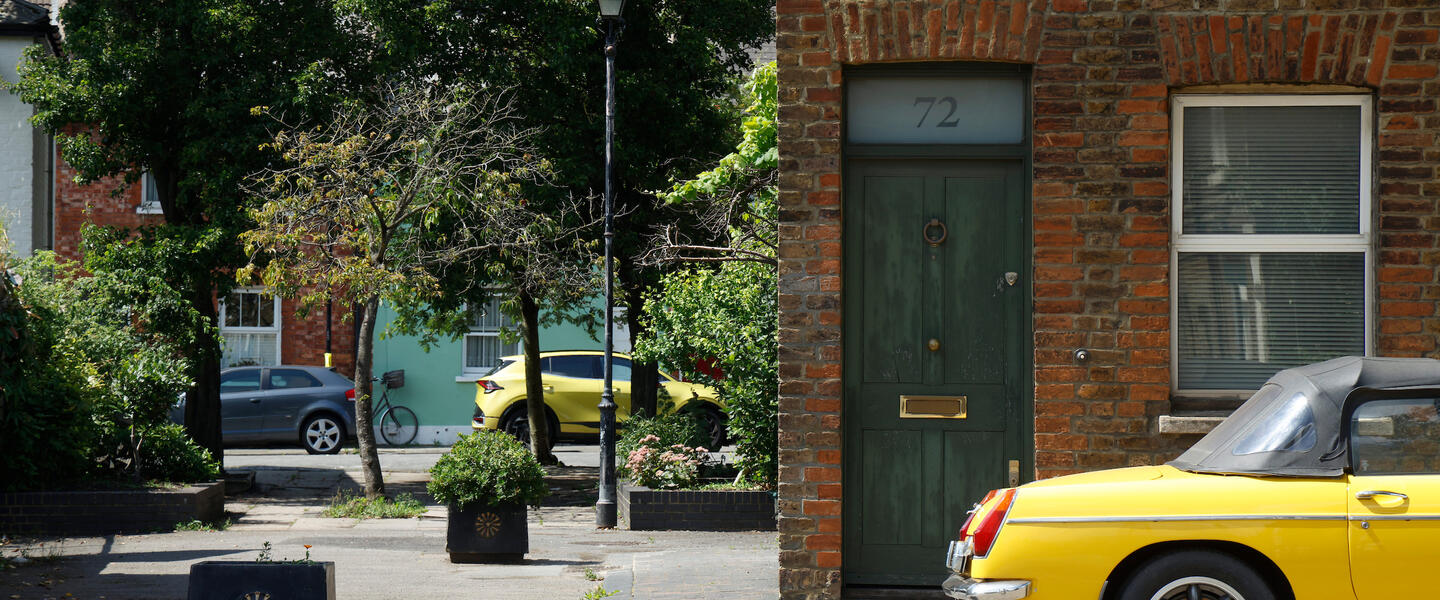 Leafy street with red brick cottages and a vintage yellow sports car