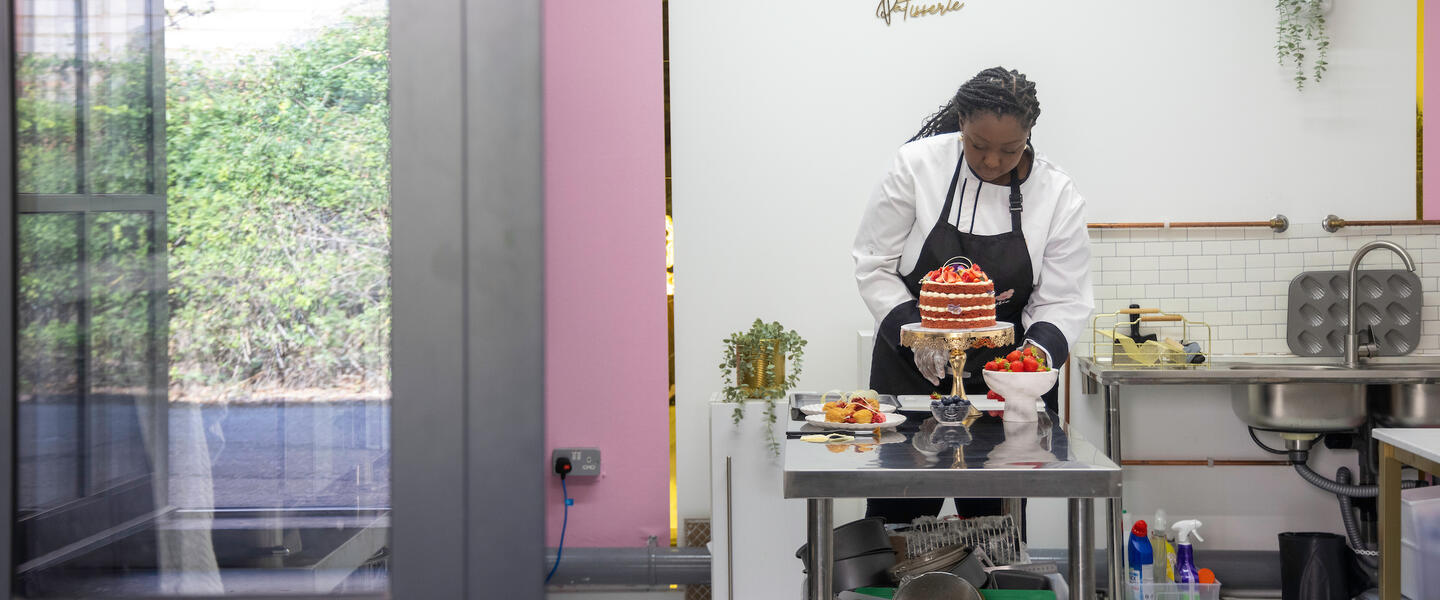 Image of a chef working in a professional kitchen, constructing a patisserie tower