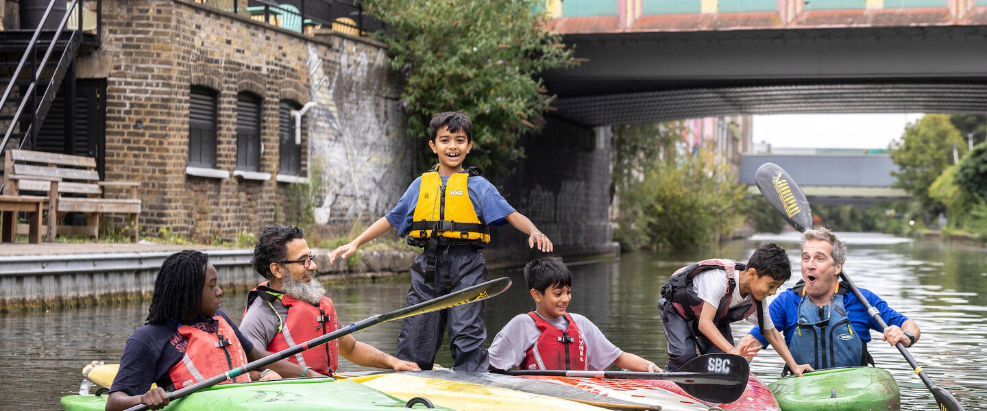 A group of 6 people in kayaks on the canal playing games