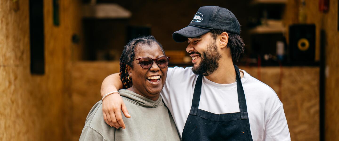 Image of a man and woman hugging in front of a shipping container which is also a burger shop.