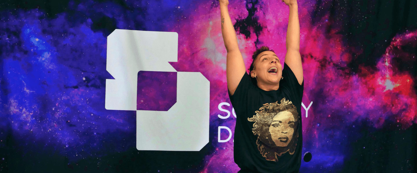 Image of a woman dancing on stage with her hands thrown in the air