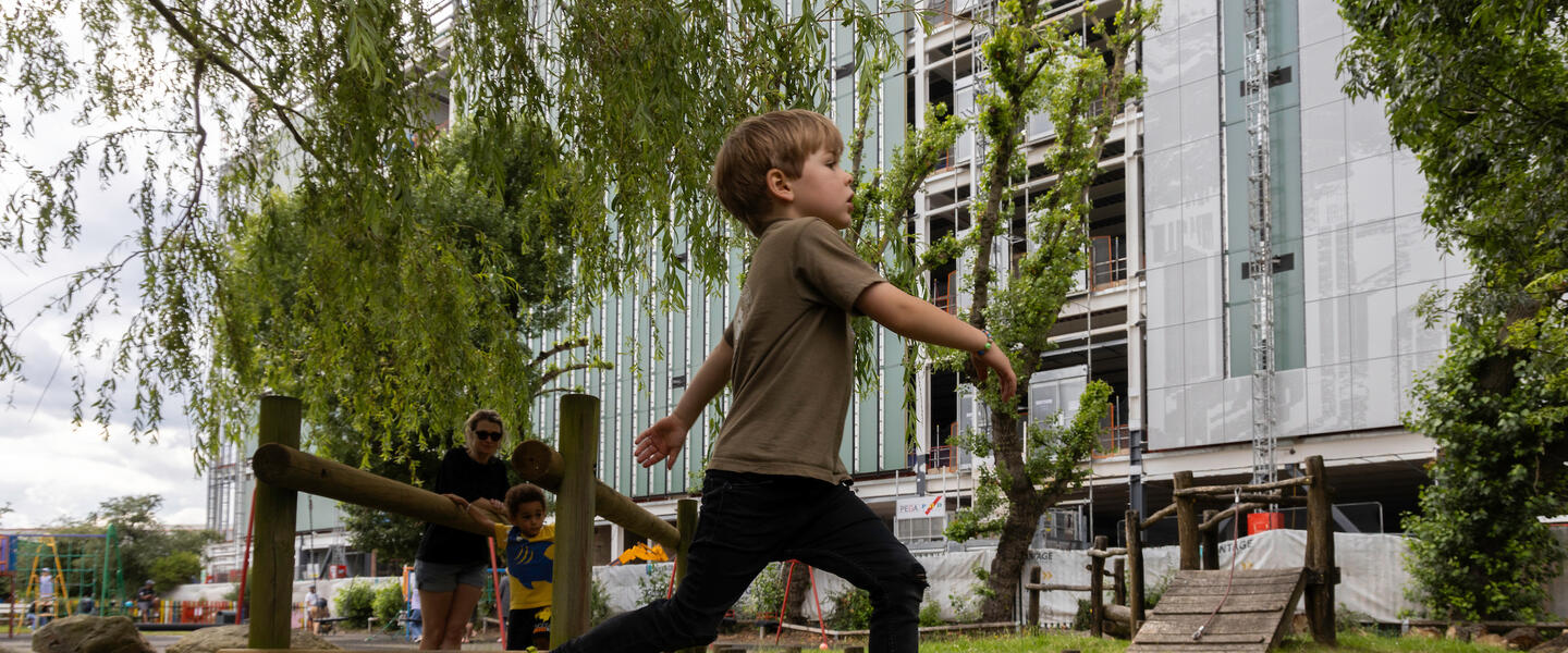 Image of a boy in a park walking across wooden stepping stones