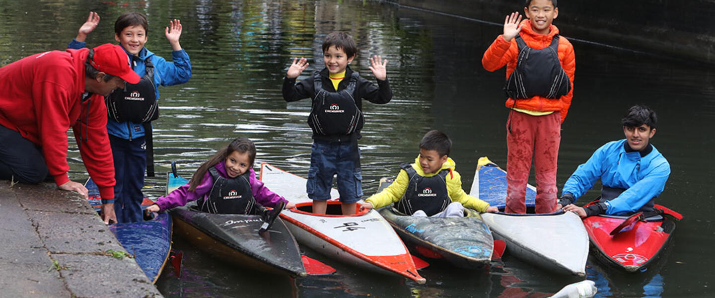Group of five children in kayaks on the canal with two teachers