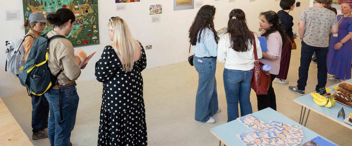 Group of people in an art gallery looking at various works of art and chatting